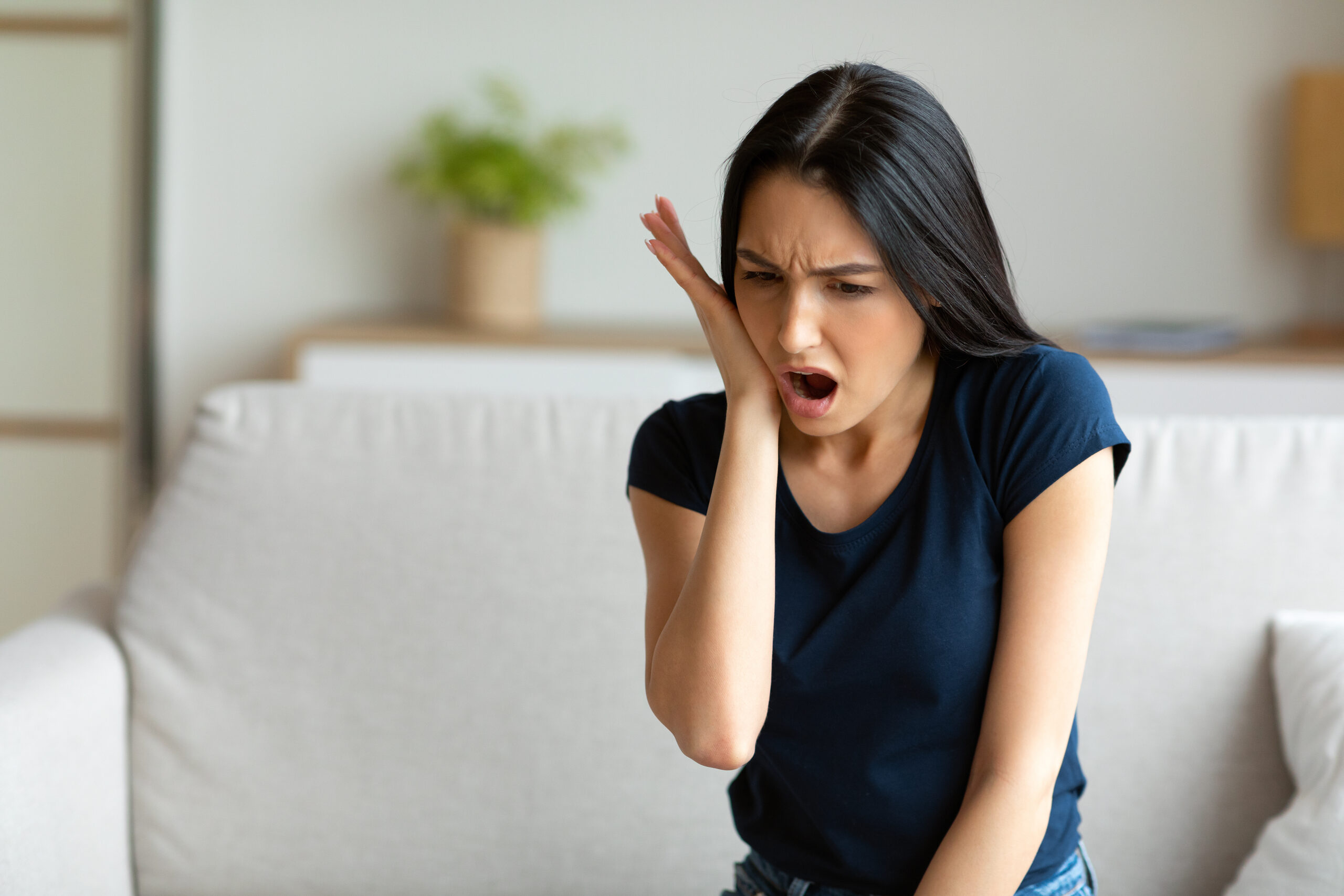 Girl Suffering From Tooth Pain Touching Cheek Sitting At Home